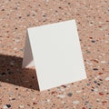 A blank, white, folded card is positioned on a speckled terrazzo surface. The surface Royalty Free Stock Photo