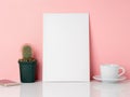 Blank white frame and plant cactus, cup of coffee or tea on a white table against the pink wall with copy space. Mockup with copy Royalty Free Stock Photo