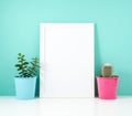 Blank white frame, plant cactus on white table against the blue wall. Mockup with copy space. Royalty Free Stock Photo