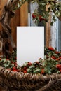 Blank white greeting card and old graceful basket. Mockup with vintage basket of vines and rose hips. Rystic style