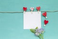 Blank white greeting card with red heart clip and purple flower on blue background Royalty Free Stock Photo