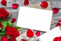 Blank white greeting card with red rose flowers bouquet and envelope with petals, lined notebook and gift box Royalty Free Stock Photo