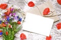 Blank white greeting card with wildflowers bouquet and envelope with flower petals