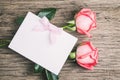 Blank white greeting paper card with pink roses and ribbon on old wooden table - Love Concept