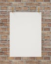 Blank white hanging poster with clothespin and rope on brick wall, background