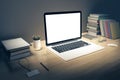 Blank white laptop screen with books and pen on wooden table, mo