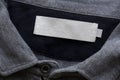 Blank white laundry care clothes label on grey fabric texture background Royalty Free Stock Photo