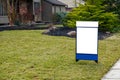 Blank white lawn sign in the grass in front of a house.