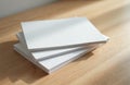 Blank white magazines catalogs stacked on wooden table surface with soft light casting shadows. Clean pages offer space for Royalty Free Stock Photo