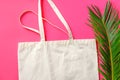 Blank white mockup linen cotton shopper tote bag green palm leaf on fuchsia pink background. Zero waste reusable nature friendly