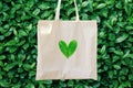 Blank white mockup linen cotton tote bag on green bush trees foliage background. Heart logo from leaves. Nature friendly style Royalty Free Stock Photo