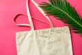 Blank white mockup linen cotton tote bag green palm leaf on fuchsia pink background. Zero waste reusable nature friendly materials