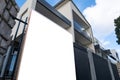 Blank white mockup template of a real estate sign board on fence with a modern multi-storey Australian luxury home at the back.