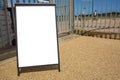 Clear street signage board placed by a closed metal gate.