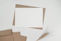 Blank white paper on brown paper envelope with Barley dry flower. Mock-up of horizontal blank greeting card. Top view of Craft