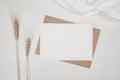 Blank white paper on brown paper envelope with Barley dry flower and white cloth. Mock-up of horizontal blank greeting card. Top Royalty Free Stock Photo