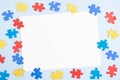 Blank white paper card with blue, yellow, red pieces of puzzle on light blue frame background. World autism awareness Royalty Free Stock Photo