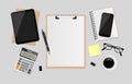 Blank white paper on clipboard with digital tablet, notebook, pen, black metallic paper clips, calculator, coffee cup, eyeglasses Royalty Free Stock Photo