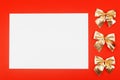 Blank white paper with golden holiday bows on red background Royalty Free Stock Photo