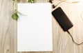 Blank a4 white paper in middle of wood table with smartphone and headphones or earphones, Top view with copy space, flat lay Royalty Free Stock Photo