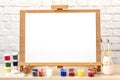 Blank white paper for painting on wooden easel on table at home studio Royalty Free Stock Photo