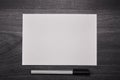 Blank white paper with pen on a wooden black desk. Close up