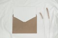 Blank white paper is placed on the open brown paper envelope with Bristly foxtail dry flower on white cloth. Mock-up of horizontal Royalty Free Stock Photo