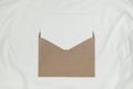 Blank white paper is placed on the open brown paper envelope on white cloth. Mock-up of horizontal blank greeting card. Top view Royalty Free Stock Photo