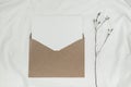 Blank white paper is placed on the open brown paper envelope with Limonium dry flower on white cloth. Mock-up of horizontal blank Royalty Free Stock Photo