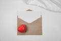 Blank white paper is placed on open brown paper envelope with red heart, White cloth. Top view of Craft envelope on white Royalty Free Stock Photo