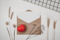 Blank white paper is placed on open brown paper envelope with red heart, Many kinds of dried flowers, White cloth on Black