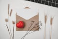 Blank white paper is placed on open brown paper envelope with red heart Many kinds of dried flowers Black cloth on white