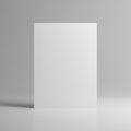 A blank white paper is placed vertically on a smooth, reflective gray surface, set agai Royalty Free Stock Photo
