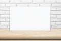 Blank white paper poster over wood table and brick wall background Royalty Free Stock Photo