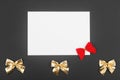 Blank white paper with red and gold christmas bows on black background Royalty Free Stock Photo