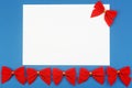 Blank white paper with red holiday bows on blue background