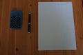 Blank white paper sheet with pen and calculator on wooden desk