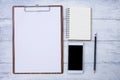 Blank white paper on wood clipboard with blank notebook and new smartphone Royalty Free Stock Photo