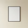 Blank white picture frame with a thin black border, centered on a beige wall. The Royalty Free Stock Photo