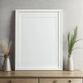 Blank white picture frame on a wooden cabinet with decorative vases and plants against a gray wall Royalty Free Stock Photo