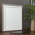 Blank white picture frame on a wooden desk with a decorative plant and grey wall background, copy space available Royalty Free Stock Photo