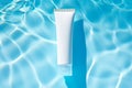 Blank white plastic tube on blue water background. Cosmetic lotion bottle cream packaging product mockup. Body care, spa Royalty Free Stock Photo