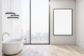 Blank white poster in black frame on light wall near big window with city view in modern style bathroom with white bath and black