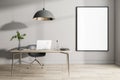 Blank white poster in black frame on light wall in sunny home office with wooden floor and table with laptop and black lamp from Royalty Free Stock Photo