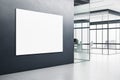 A blank white poster on a dark wall inside a modern office corridor with glass partitions and an outdoor view, concept of Royalty Free Stock Photo