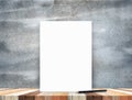 Blank white poster leaning at tropical wood table top with dark