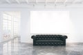 Blank white poster on white wall with black leather sofa on concrete floor, mock up Royalty Free Stock Photo