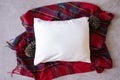 Blank white rectangle cushion laying on a tartan/plaid scarf