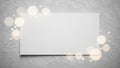 Blank white rectangular card or paper placed on a textured gray concrete wall with soft bokeh light effects Royalty Free Stock Photo