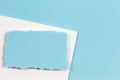 Blank white ripped piece of paper, torn paper card on white and light blue background. Top view Royalty Free Stock Photo